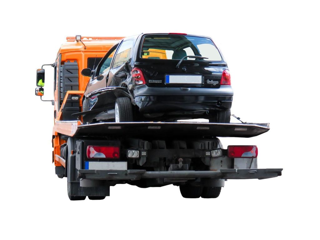 Black car being towed on a flatbed truck, illustrating emergency towing services provided by Lititz Collision for vehicle recovery after accidents.
