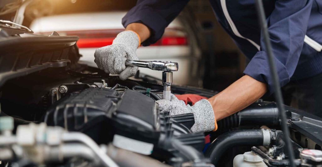 Mechanic using a wrench to repair an engine, highlighting auto body repair services relevant to collision repair pricing in Lititz, PA.