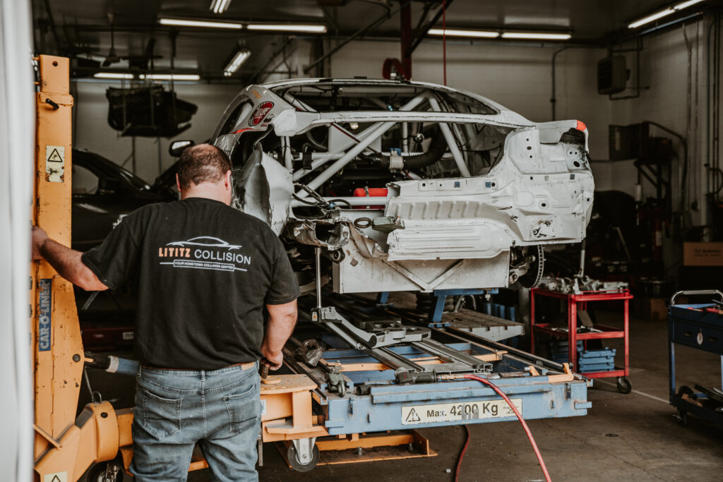 Auto body technician at Lititz Collision working on a vehicle frame in a repair shop, showcasing collision repair expertise and equipment.